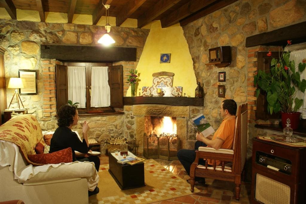 Dos personas en el salón con chimenea de la Casa rural Heredad de la Cueste